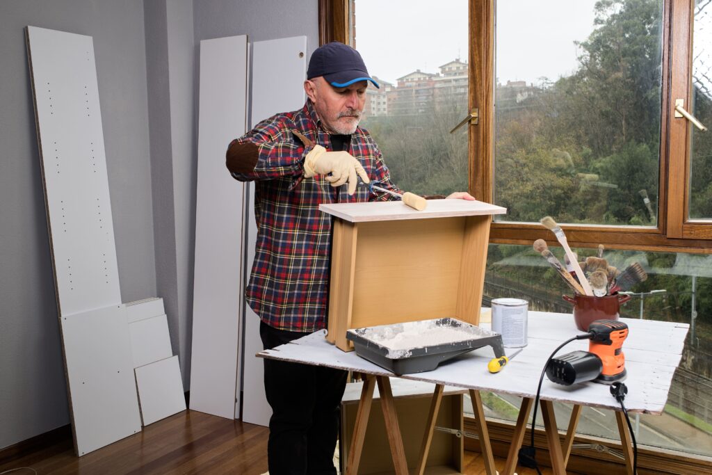 A man paints a drawer of a cabinet.