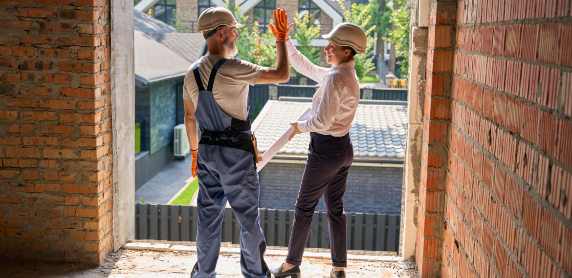 Two construction supervisors giving high fives to each other after a successful home restoration project.