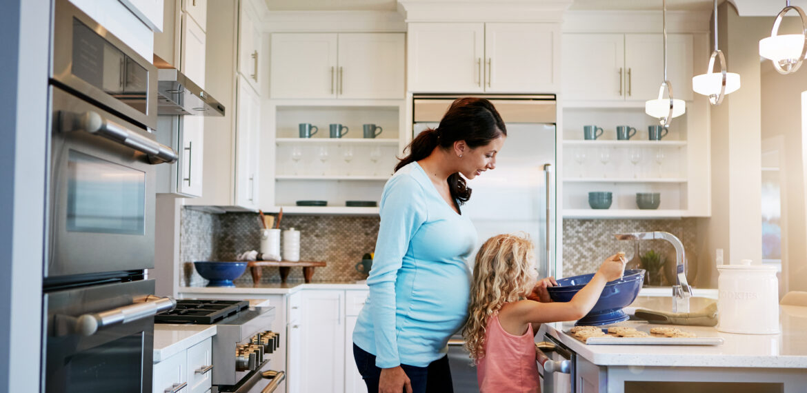 A daughter helping a mom to make sweet treats in the kitchen.