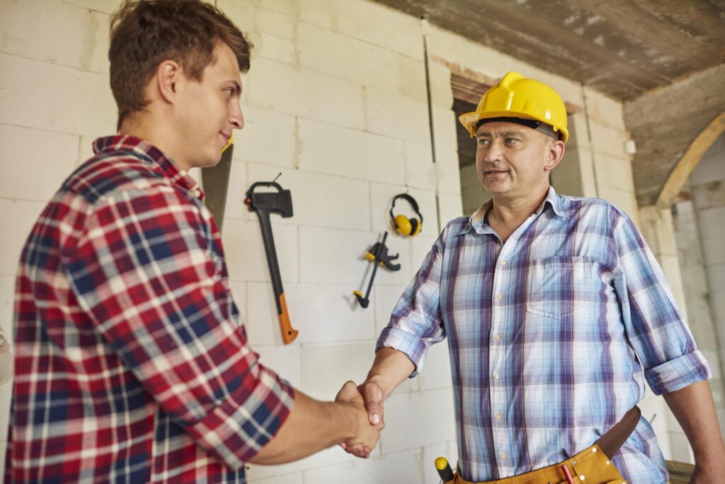 A male client (L) shakes hands with a senior home remodeler.